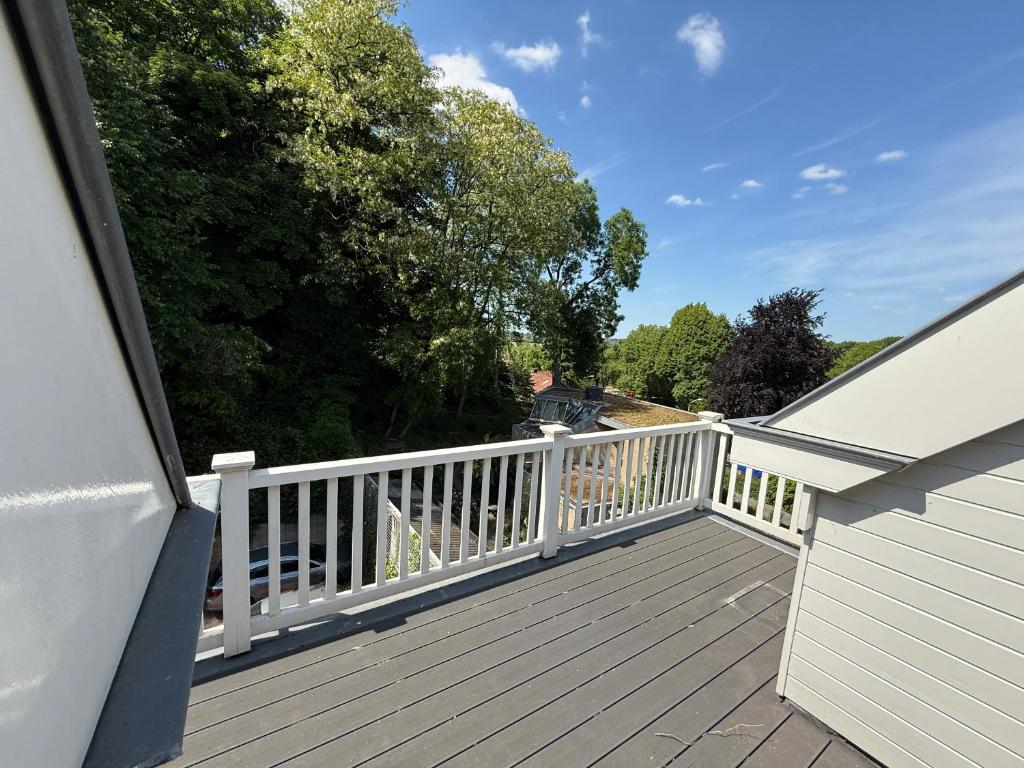a wooden deck with a white fence and trees at Luxe Penthouse nabij Nijmegen in Ubbergen
