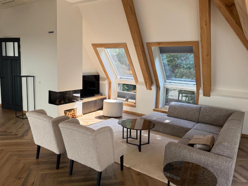 a living room with a couch and chairs and a tv at Luxe Penthouse nabij Nijmegen in Ubbergen