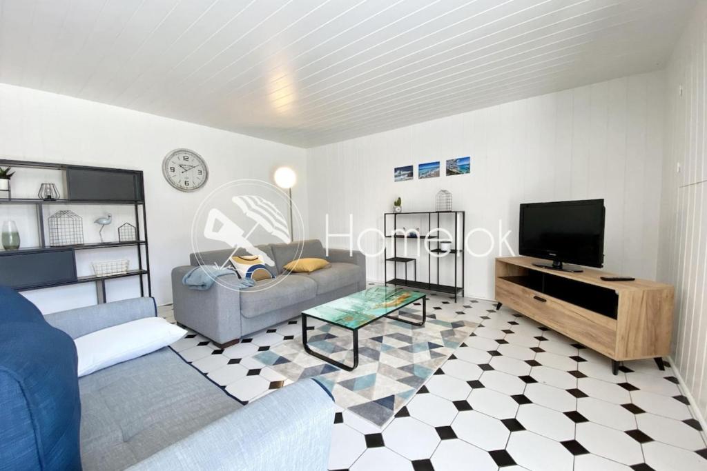 a living room with a couch and a tv at Longère de charme cosy - Proche des plages in Ploemeur