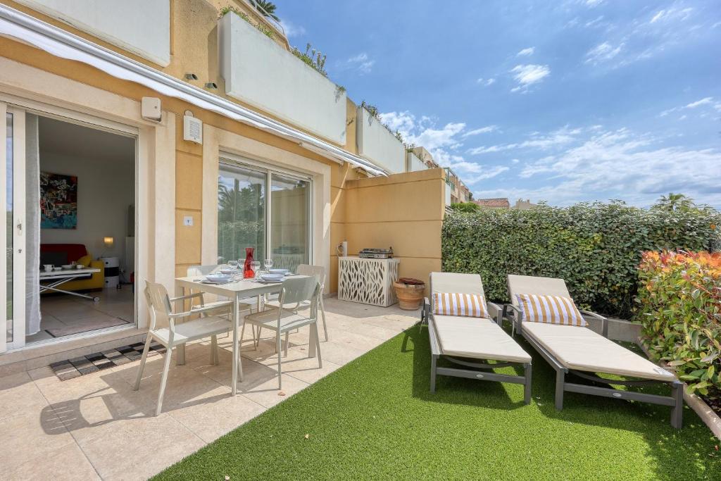 une terrasse avec une table et des chaises sur une pelouse dans l'établissement Le Toy Palm - 5min à Pied de la Plage, à Sanary-sur-Mer
