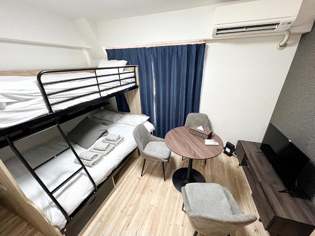 Zimmer mit einem Etagenbett, einem Tisch und Stühlen in der Unterkunft サンシティ大濠公園 in Susakiuramachi