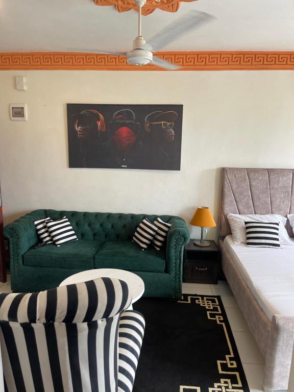 a living room with a green couch and a bed at bamburi studio in Mombasa