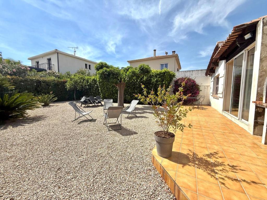 un patio avec des chaises et une table et une maison dans l'établissement Maison 3 pieces, à Villeneuve-Loubet