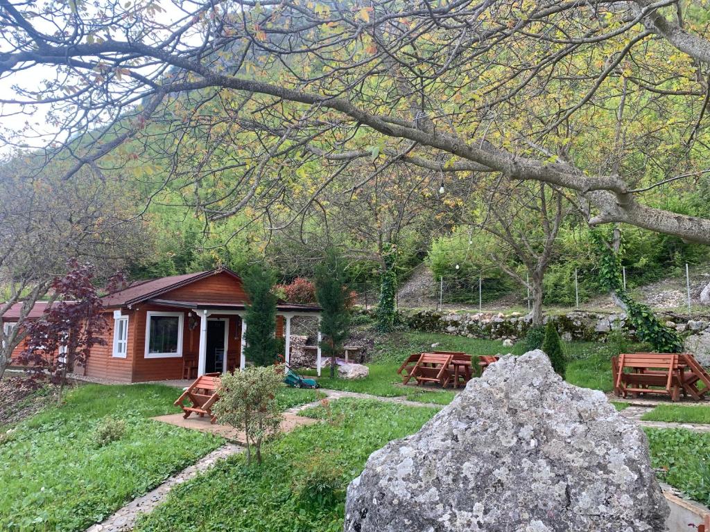 a small house with a rock in the yard at Bujtina Shpella e Plakës Çerçan Librazhd in Librazhd