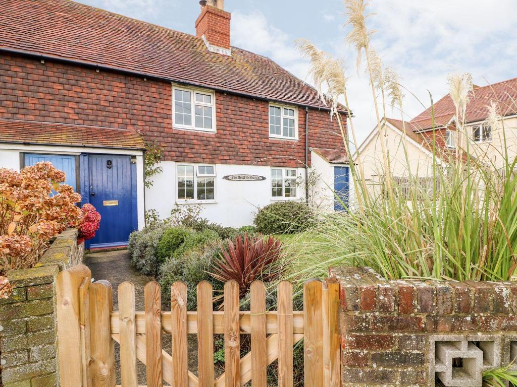 a house with a blue door and a fence at 2 Seaview Cottages in Pevensey