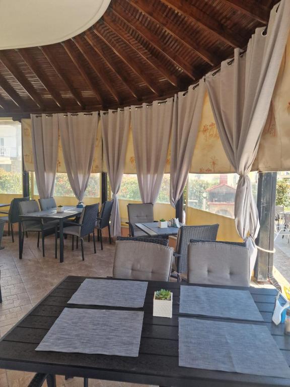 a restaurant with tables and chairs and curtains at Pension Delfini in Asprovalta