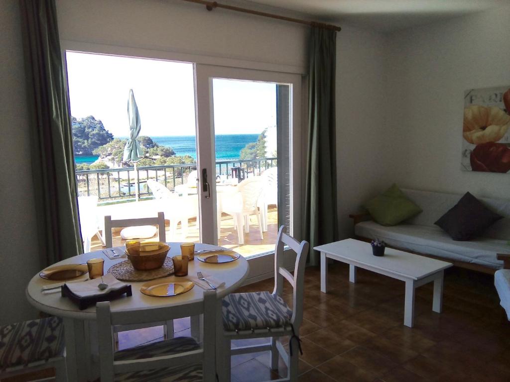 a living room with a table and a view of the ocean at Apartamentos Encanto Del Mar in Cala Galdana