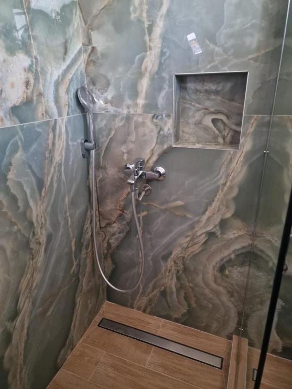 a shower in a bathroom with a marble wall at Pension Delfini in Asprovalta