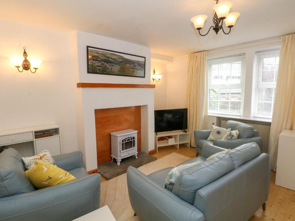 a living room with two blue couches and a fireplace at Holme Cottage in Hebden Bridge
