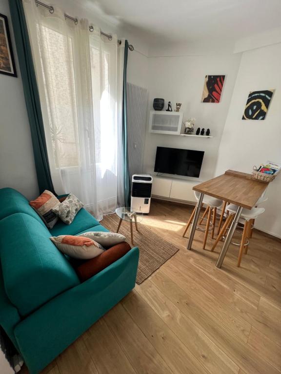 un salon avec un canapé bleu et une table dans l'établissement T2 centre ville de Nice face de la gare routière Nice ville, à Nice