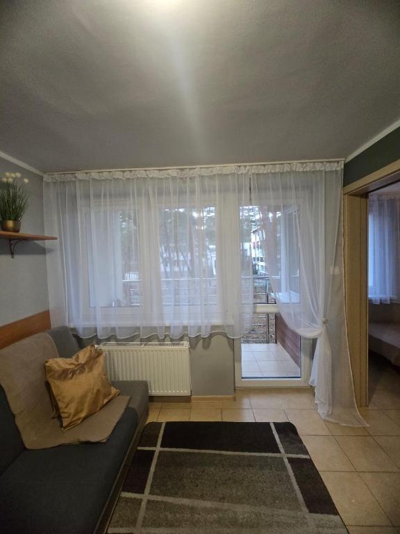 a living room with a couch and a window at Ośrodek Wczasowy Bursztyn in Gdańsk