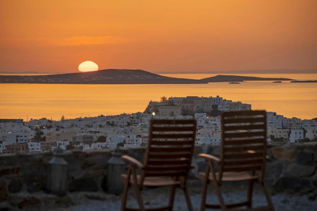 two chairs sitting in front of a city at sunset at Amenti Horizon View in Agkidia