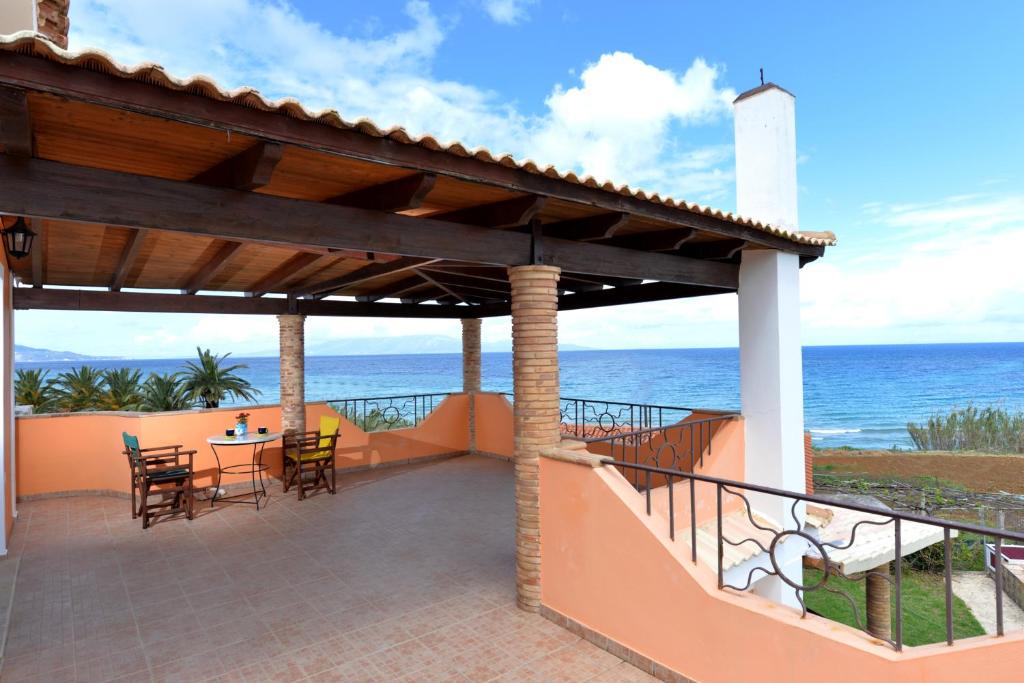 Galini Beach Villa في أمودي: شرفة مع طاولة وكراسي والمحيط