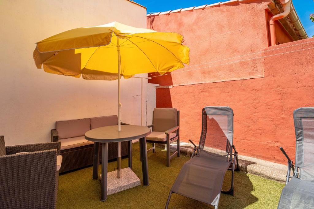 - une table avec un parasol jaune sur la terrasse dans l'établissement Maison de pecheurs, à Valras-Plage