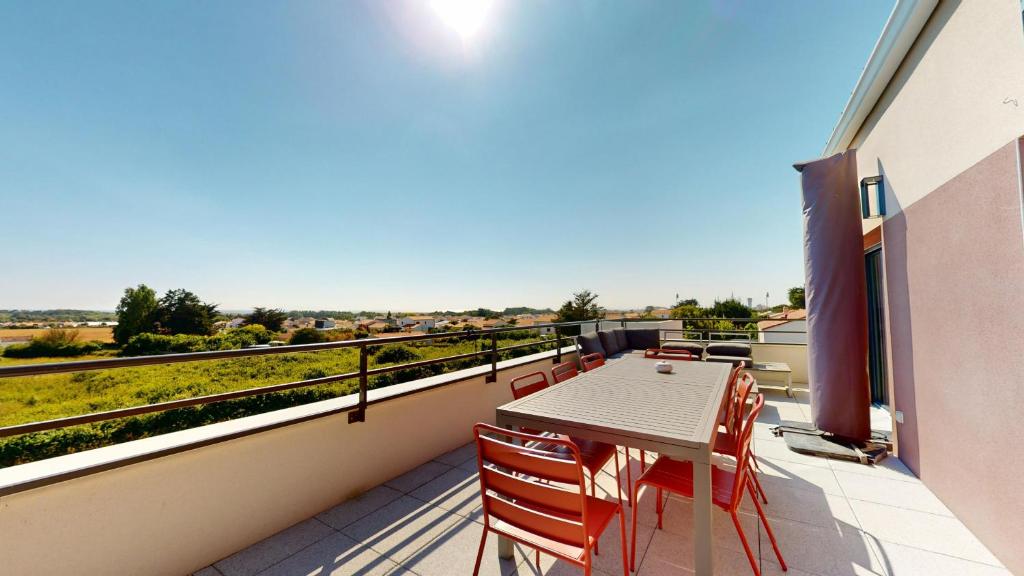 un patio avec une table et des chaises sur un balcon dans l'établissement Cap Littoral vue mer et campagne, à Saint-Gilles-Croix-de-Vie
