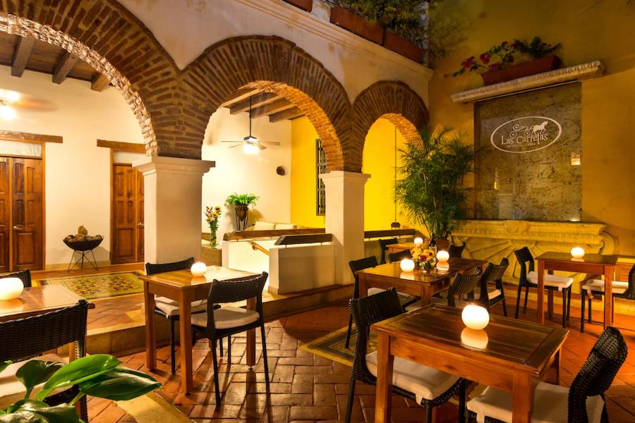 a restaurant with tables and chairs and a kitchen at Hotel Boutique Las Carretas in Cartagena de Indias