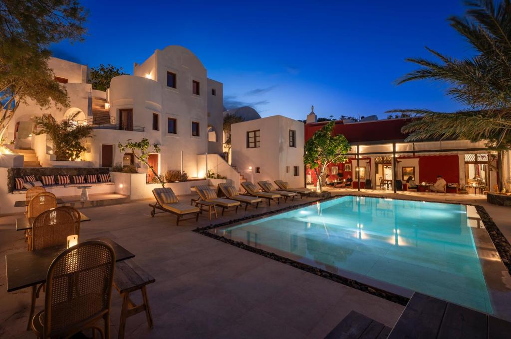an outdoor swimming pool with chairs and a house at Meroviglia Boutique Hotel in Imerovigli