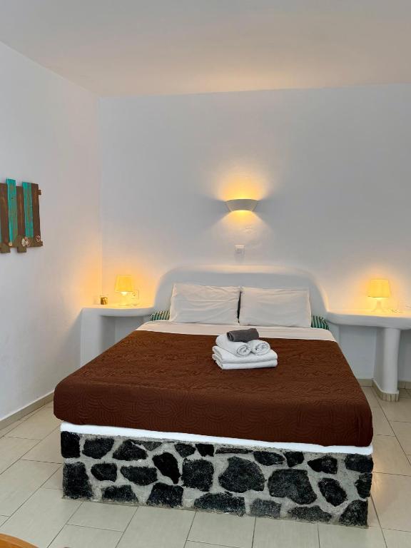 a bedroom with a large bed with a brown blanket at Manias Fira Residences in Fira