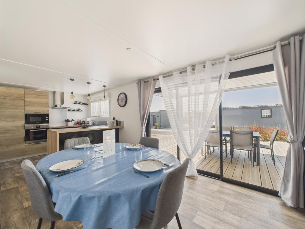 a dining room with a blue table and a kitchen at Chalet pour 6, residence avec piscine in Brétignolles-sur-Mer