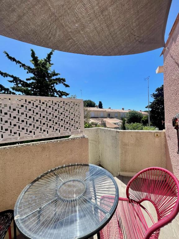 une table en verre et deux chaises roses sur la terrasse dans l'établissement 