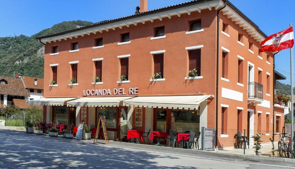 a building with red tables and chairs on a street at Locanda Del Re in Feltre