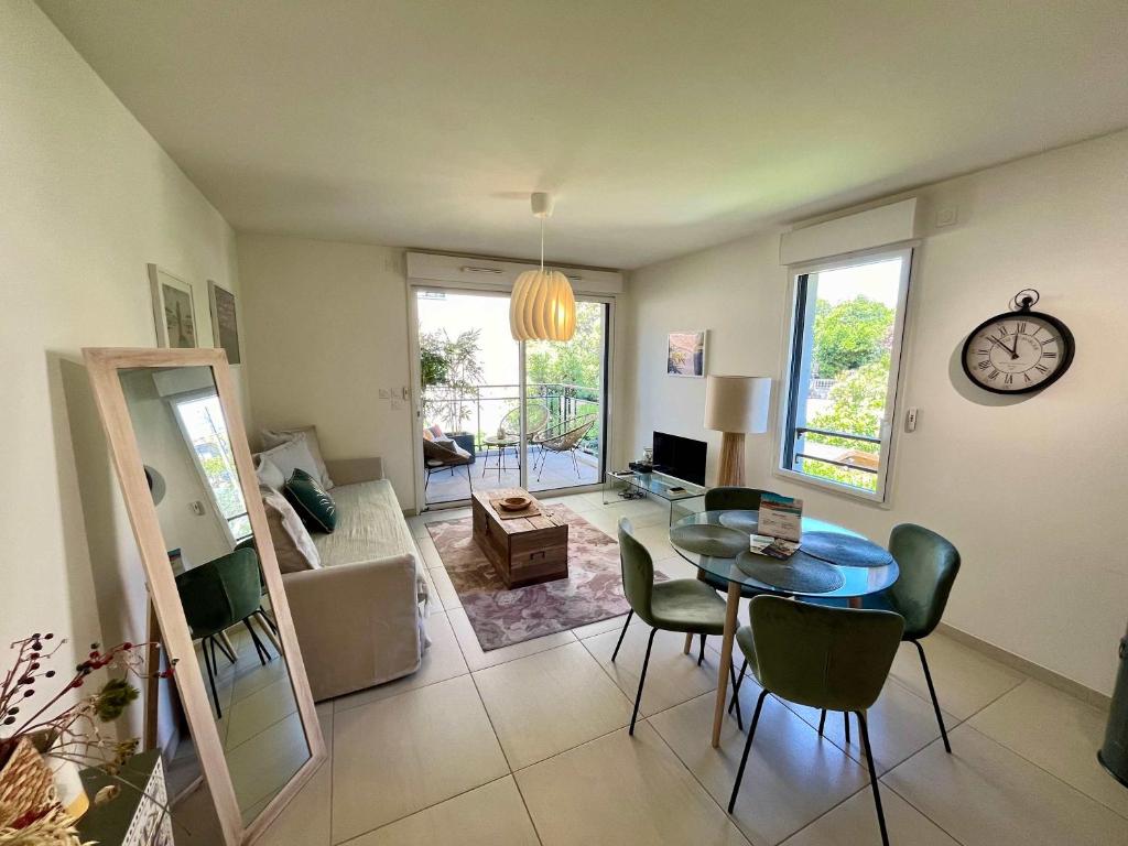 - un salon avec une table, des chaises et une horloge dans l'établissement B035 Magnifique appartement neuf a deux pas du centre, à Cannes