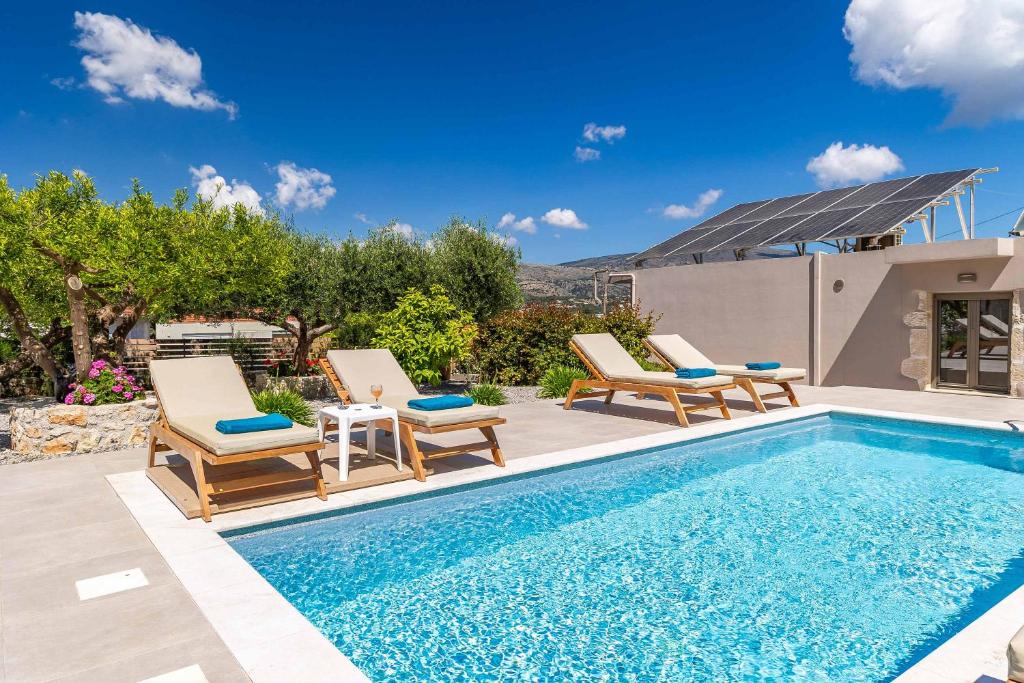 a swimming pool with two lounge chairs next to a house at Villa Eva Chania in Neo Chorio