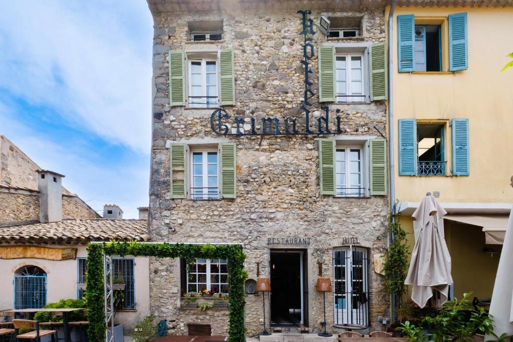 un vieux bâtiment en pierre avec des fenêtres vertes à volets dans l'établissement Grimaldi, à Cagnes-sur-Mer