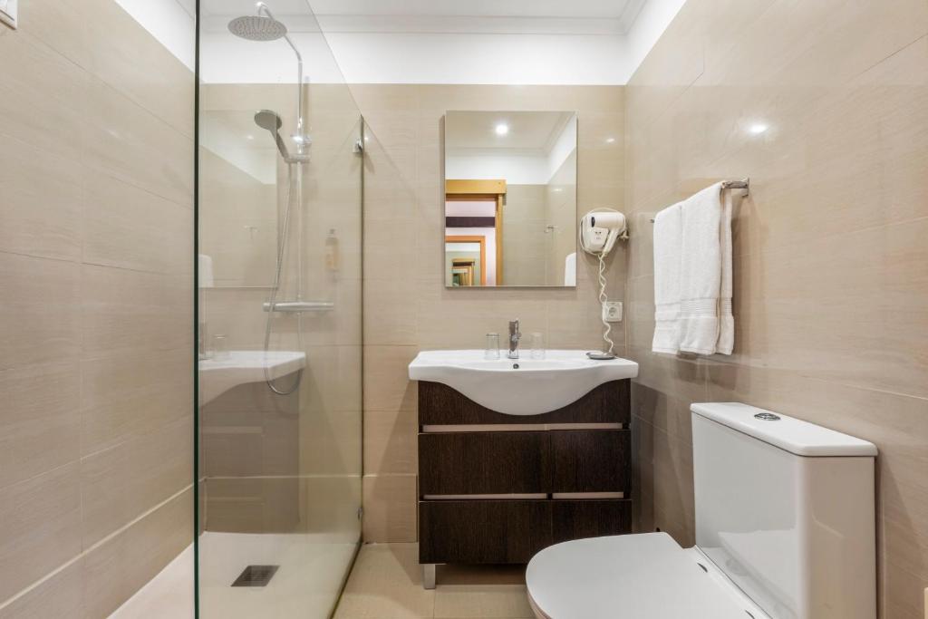 a bathroom with a toilet and a sink and a shower at White Waters Hotel in Machico