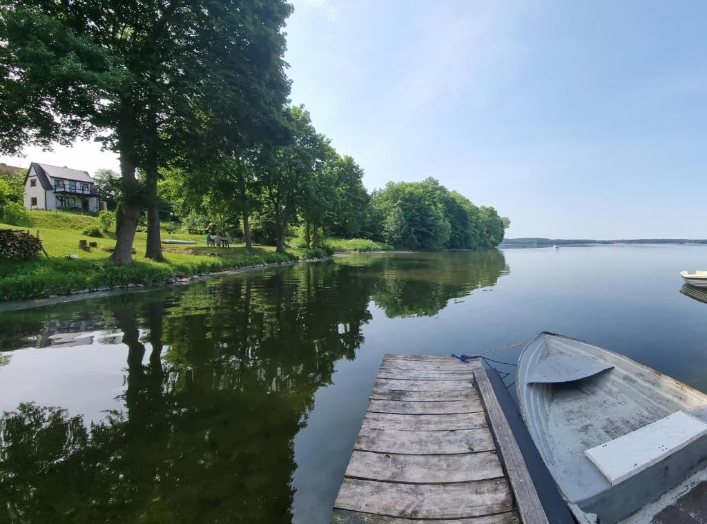 a boat parked next to a dock on a river at Domek nad jeziorem Gołdopiwo in Jeziorowskie