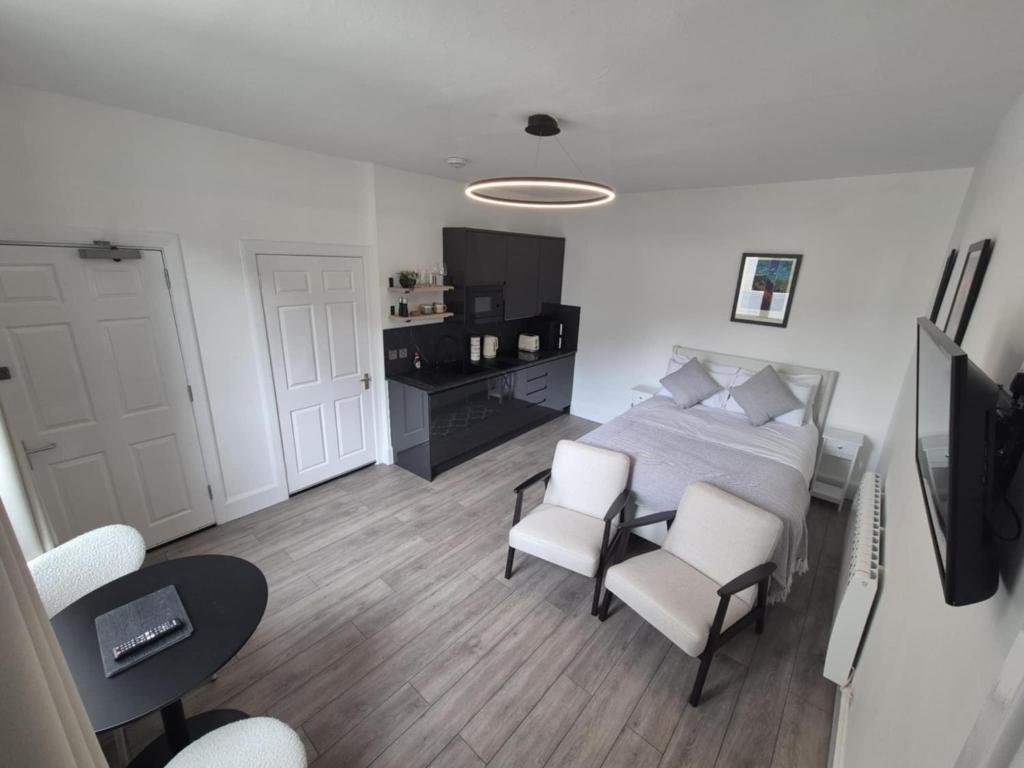 a bedroom with a bed and two white chairs at MacKaw Flat 2 in Fort William