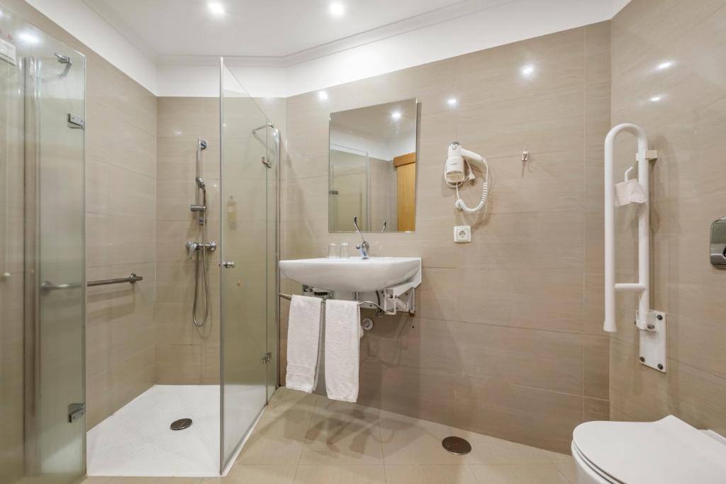 a bathroom with a sink and a shower and a toilet at White Waters Hotel in Machico