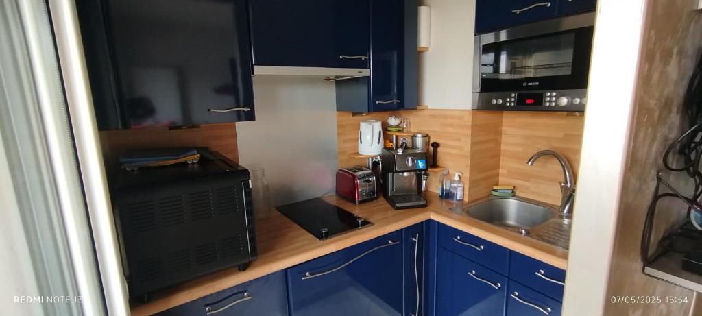 La cuisine est équipée de placards bleus, d'un évier et d'un four micro-ondes. dans l'établissement Studio with balcony near city center, à Courseulles-sur-Mer
