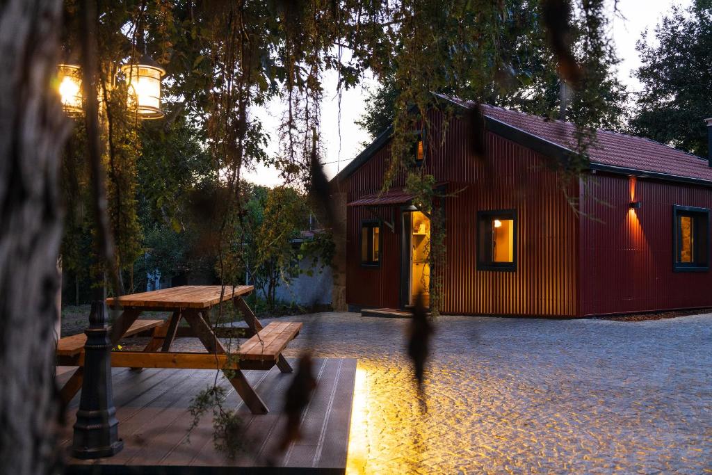 uma mesa de piquenique em frente a um prédio vermelho em Quintinha do Varoso - Little Red Cottage House em São Pedro do Sul