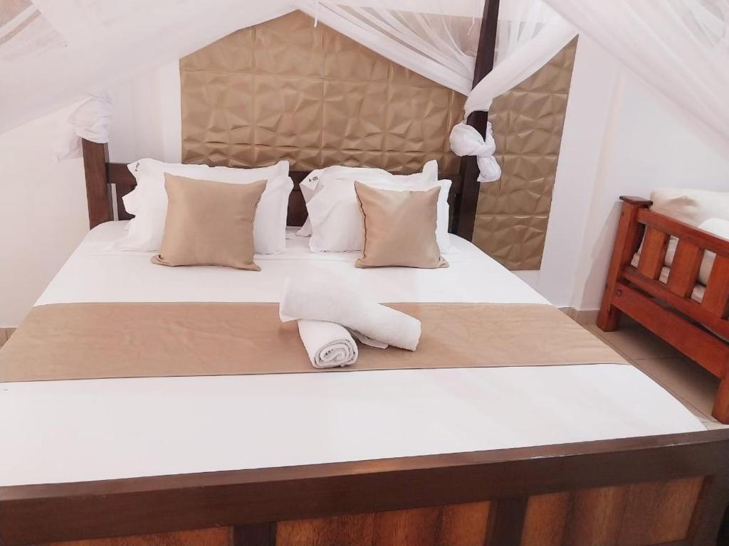 a white bed with two towels on it at Diani Studio with 3 Pools & Balcony in Diani Beach