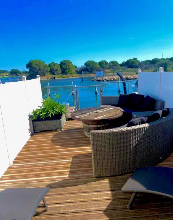 une terrasse en bois avec une table et des chaises sur un bateau dans l'établissement Marina très belle vue avec ponton, au Grau-du-Roi