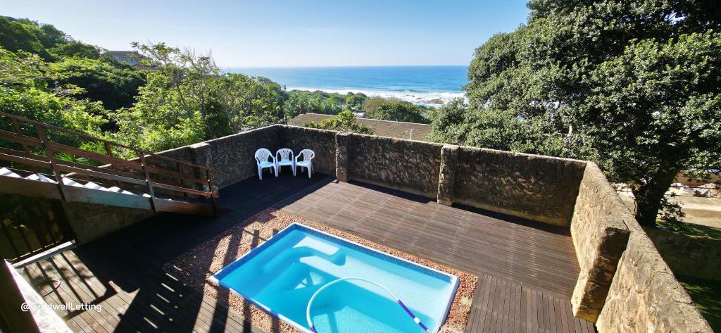 a swimming pool with two chairs and the ocean at Beachwood Cottage in Margate