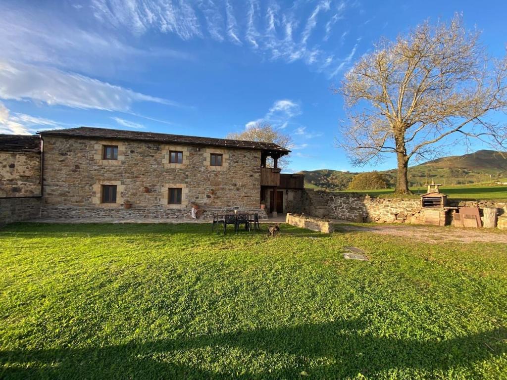 an old stone building with a tree in a field at Cabaña Pasiega Lucas in Bustantegua