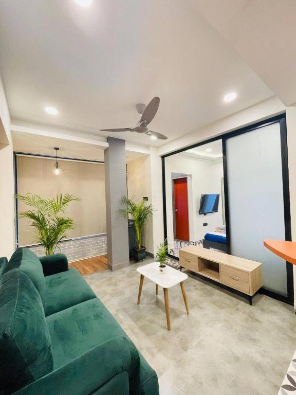 a living room with a green couch and a large window at Hostique Blossom, Private Studio for Staycation in Indore