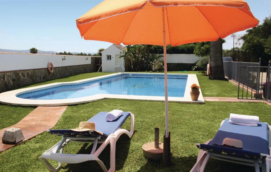 2 sillas y sombrilla junto a la piscina en Dehesa Las Yeguas en Benalup - Casas Viejas