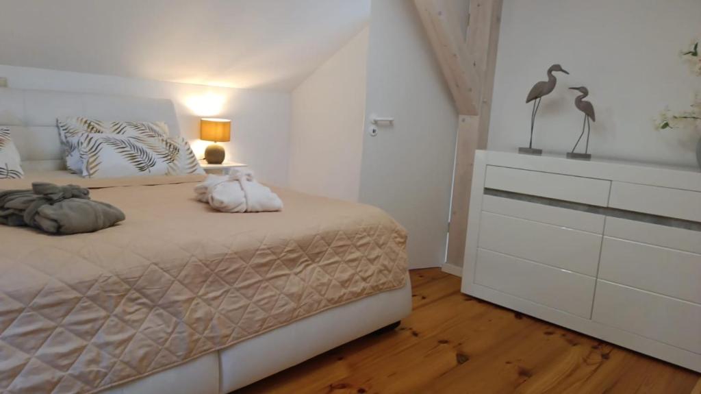 ein weißes Schlafzimmer mit einem Bett und einer Kommode in der Unterkunft Luxus Summer Breeze Ferienhaus Lübbesee Sauna Bootssteg Templin in Milmersdorf