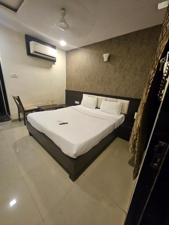 a bedroom with a bed with white sheets and pillows at Prime Hotel Addore Palácée - Near Mumbai Airport , Visa Consultant , Jio World Convention Centre BKC in Mumbai
