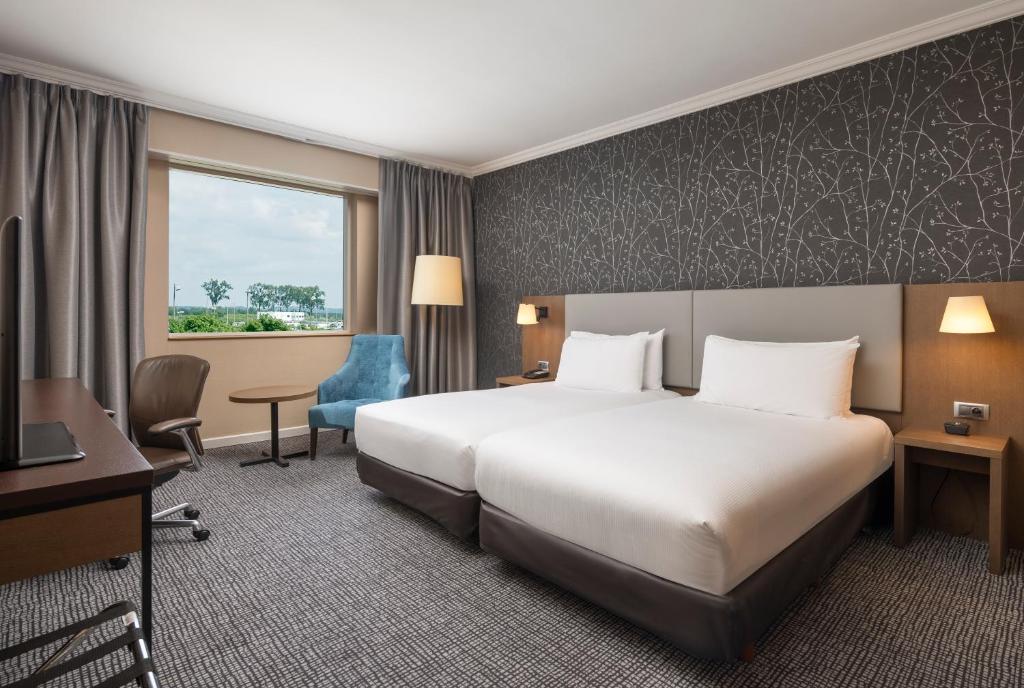 a hotel room with a large bed and a desk at Hilton Paris Charles De Gaulle Airport in Roissy-en-France