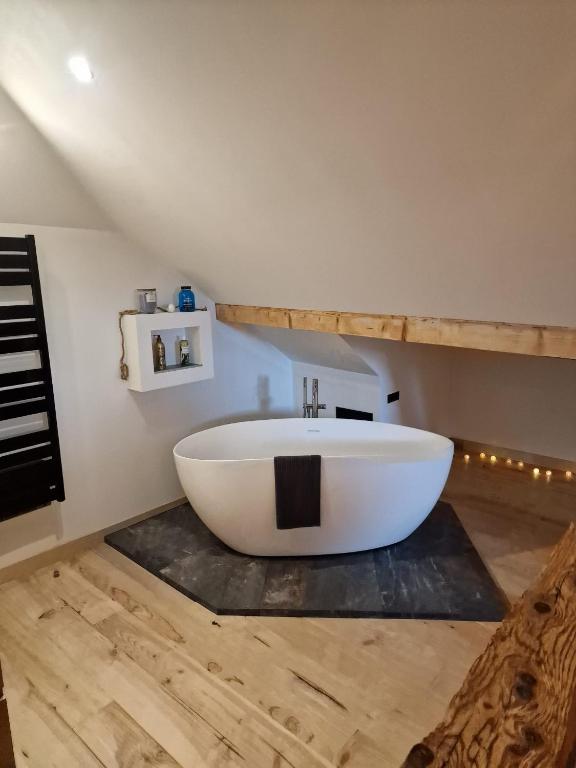 une grande baignoire blanche sur un plancher en bois dans une salle de bain dans l'établissement Duplex la Beun, à Saint-Paul-en-Chablais