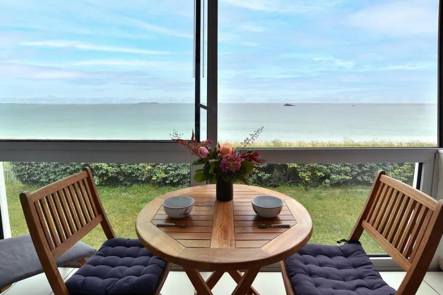une table en bois avec deux chaises et un vase avec des fleurs dans l'établissement Le grand jardin, à Saint-Malo