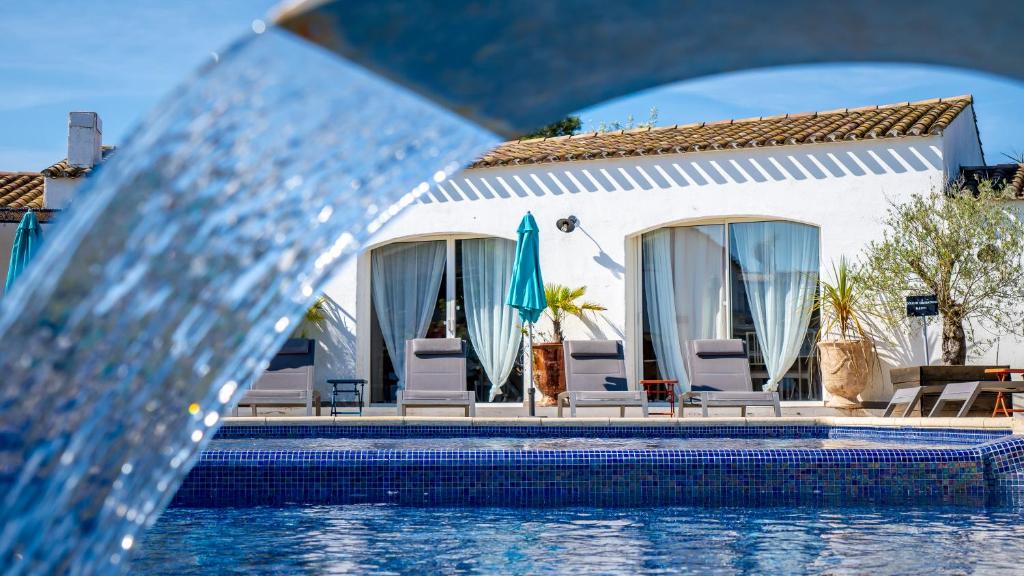 a pool with a fountain in front of a house at Hotel La Tramontane in Saintes-Maries-de-la-Mer