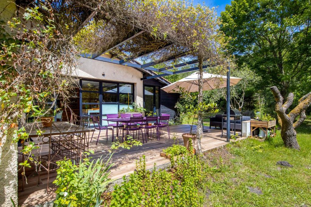a patio with purple tables and chairs and an umbrella at La maison du Médoc in Avensan
