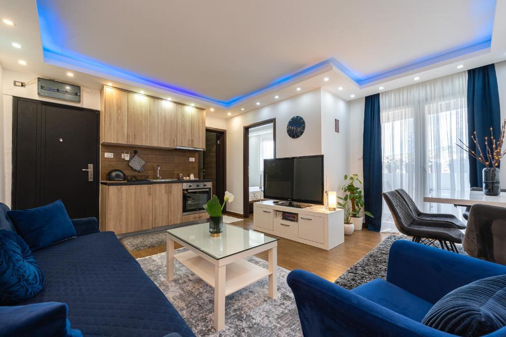 a living room with blue couches and a tv at BlueMont Apartment in Podgorica
