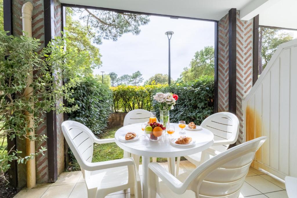 une table blanche et des chaises sur une terrasse dans l'établissement Appartement proche océan - piscine - terrasse - parking, à Moliets-et-Maa