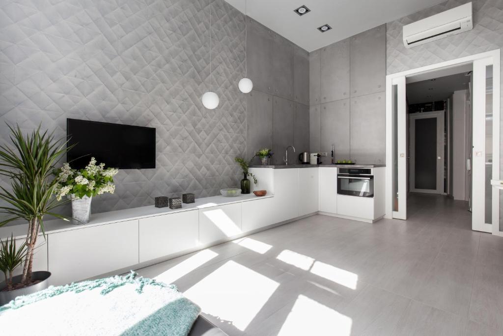 a kitchen with white cabinets and a tv on a wall at Boutique Apartment in Budapest Downtown in Budapest